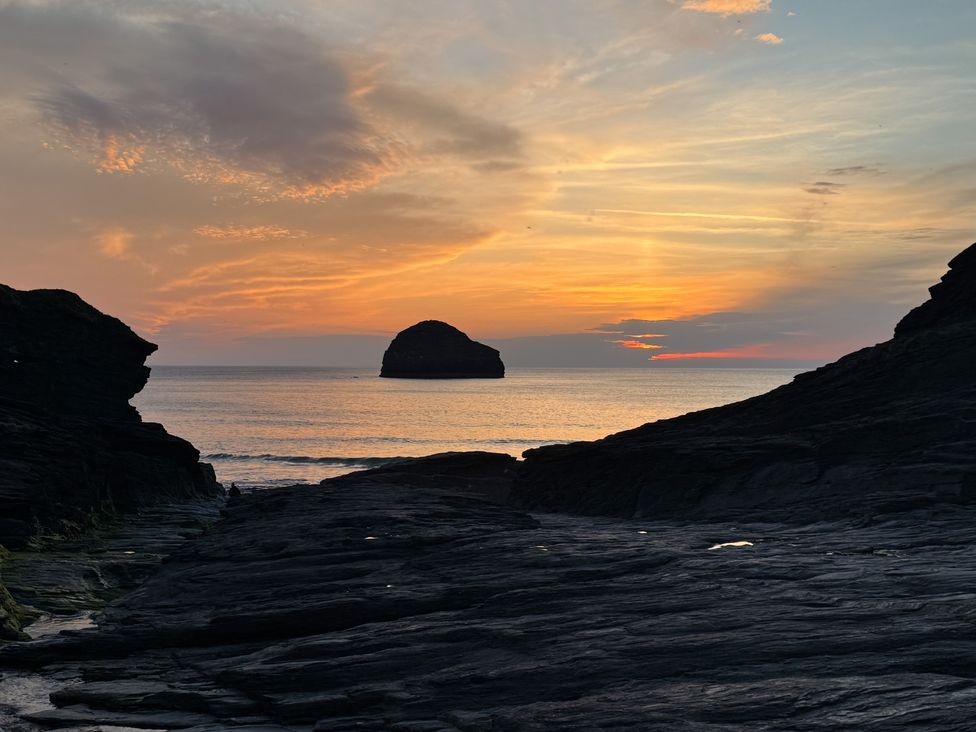 A view of the sunset over the sea with rock formations at Hilldene Treknow