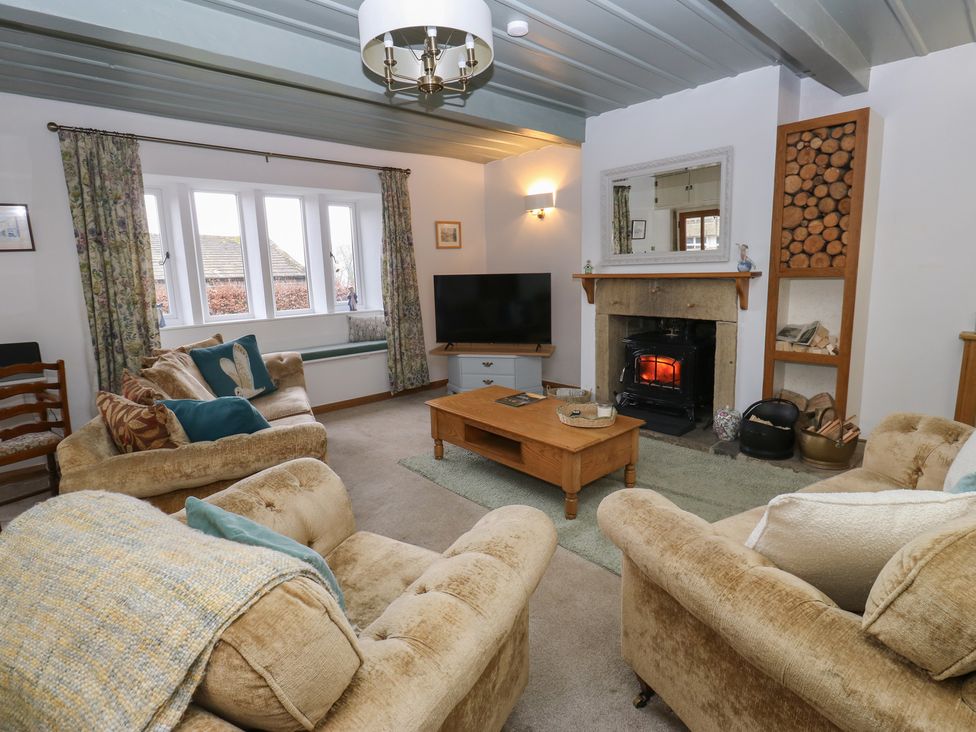 A living room with a fireplace and a television at Barley Cote Farm in Riddlesden