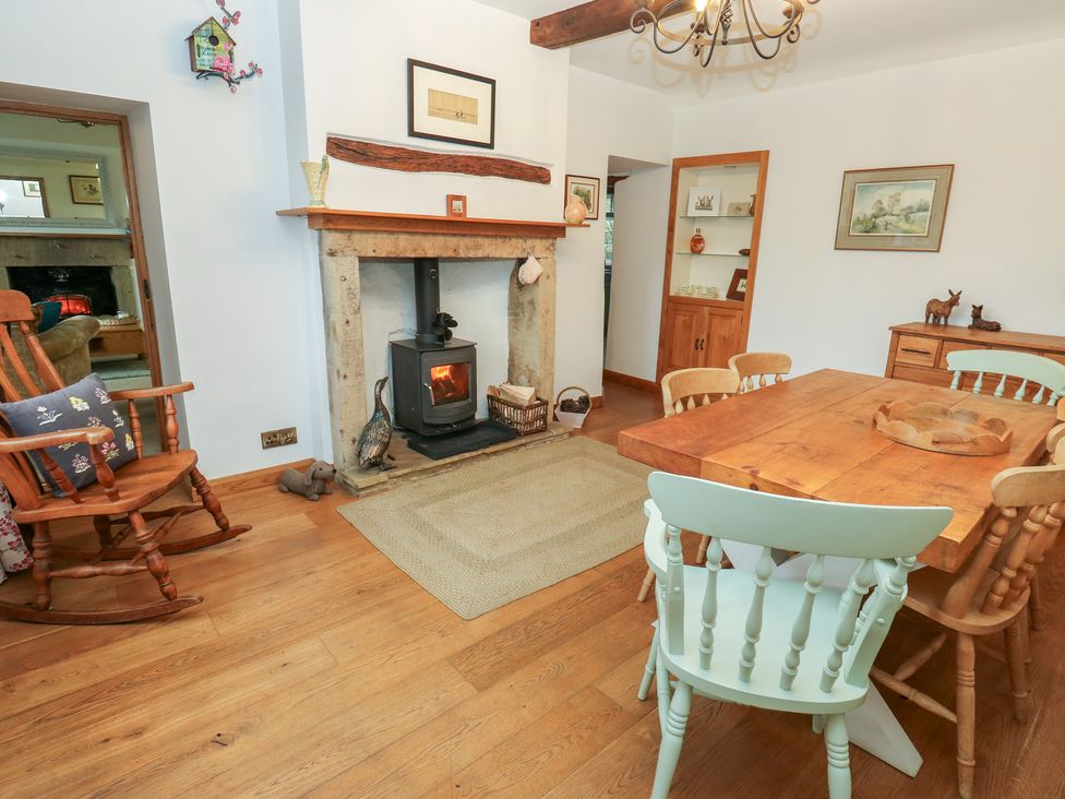 A dining room with a wooden table and a fireplace at Barley Cote Farm in Riddlesden