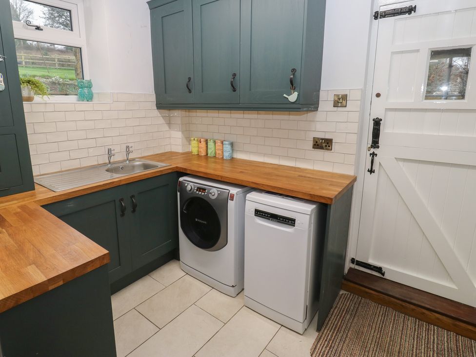 A kitchen with a sink, washing machine, and dishwasher at Barley Cote Farm in Riddlesden