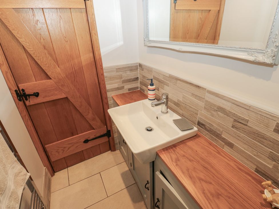 A bathroom with a sink and wooden door at Barley Cote Farm in Riddlesden