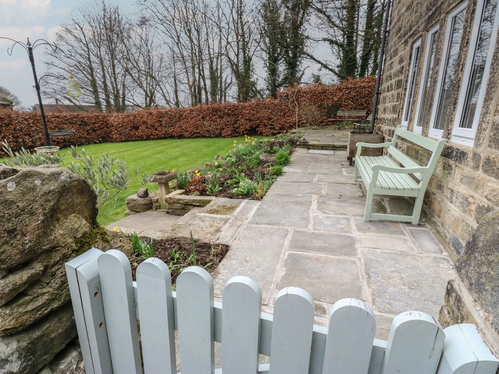 A garden with a stone pathway and green bench at Barley Cote Farm in Riddlesden