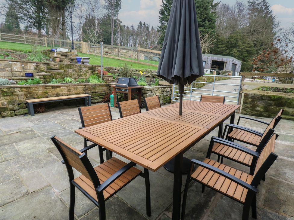 A garden with a table and chairs under an umbrella at Barley Cote Farm in Riddlesden