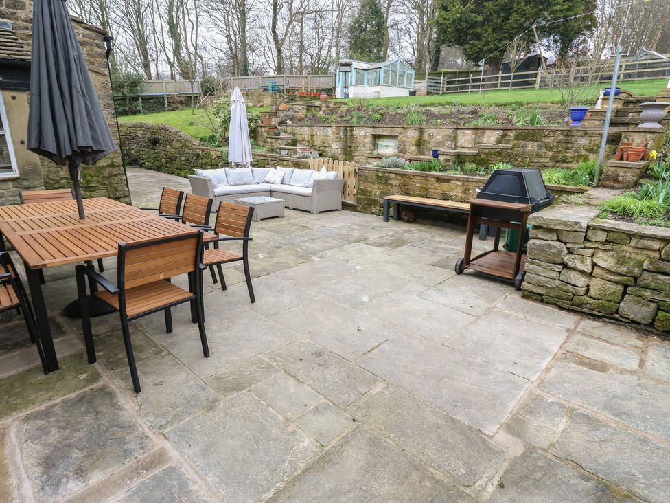 A garden with a dining table and chairs at Barley Cote Farm in Riddlesden