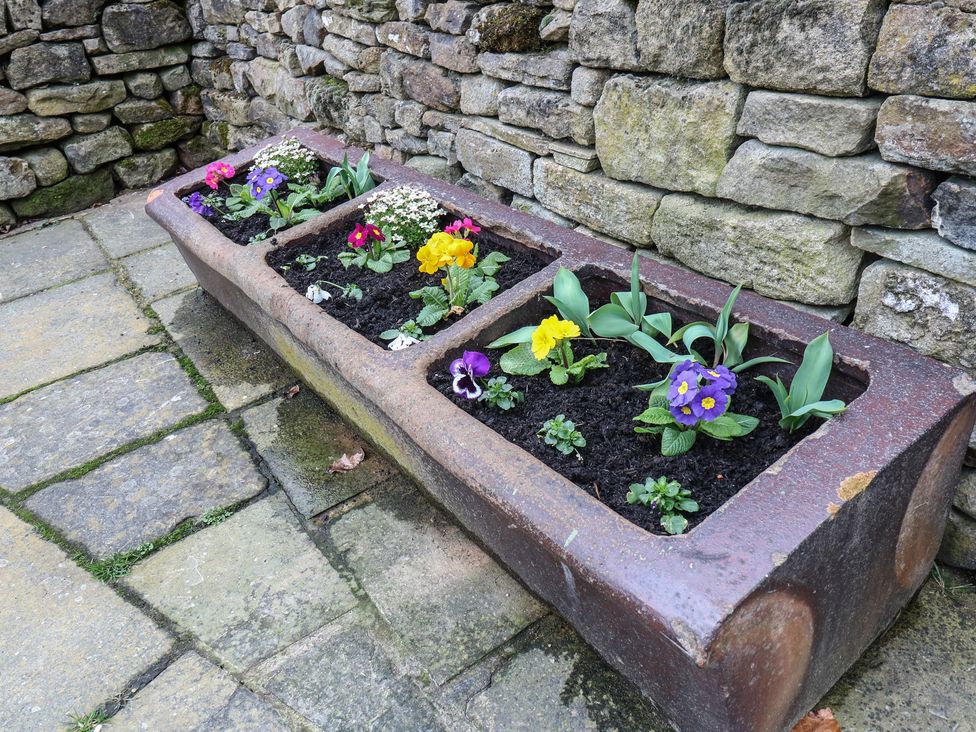 A flower bed with various flowers beside a stone wall at Barley Cote Farm Riddlesden