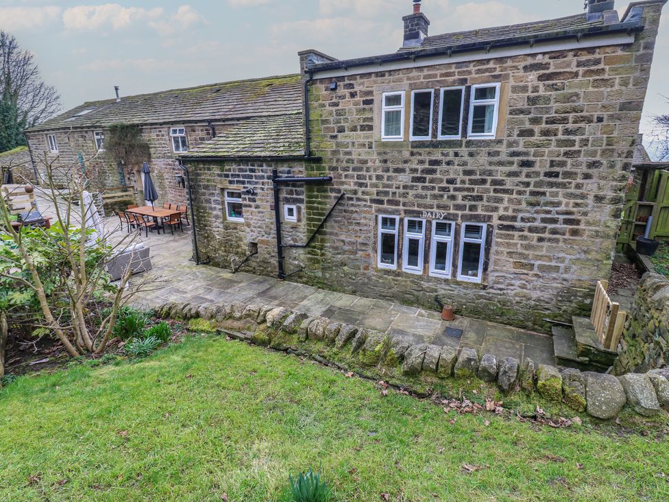 An outdoor view of a stone building and patio at Barley Cote Farm in Riddlesden