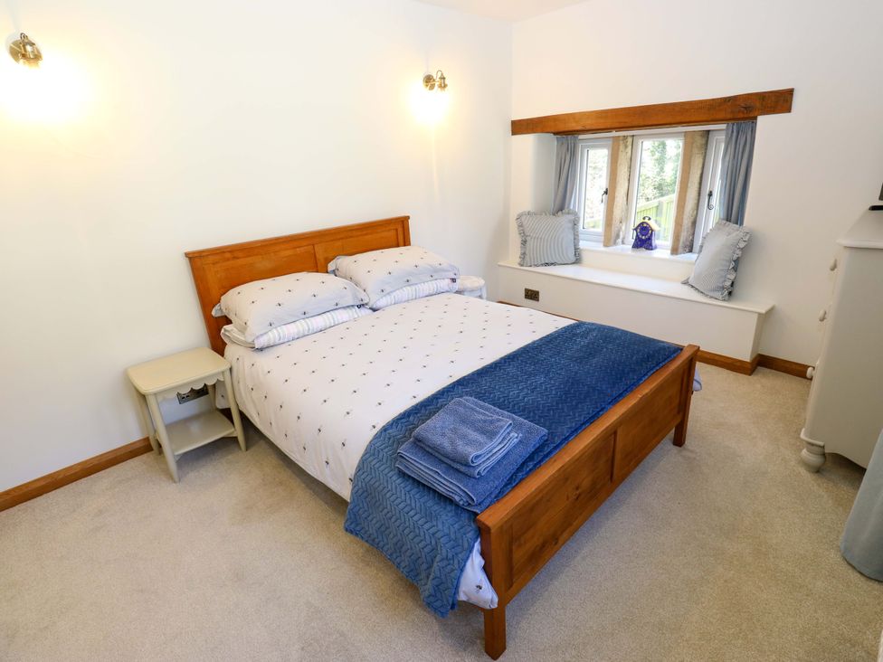 A bedroom with a bed and bedside table at Barley Cote Farm in Riddlesden