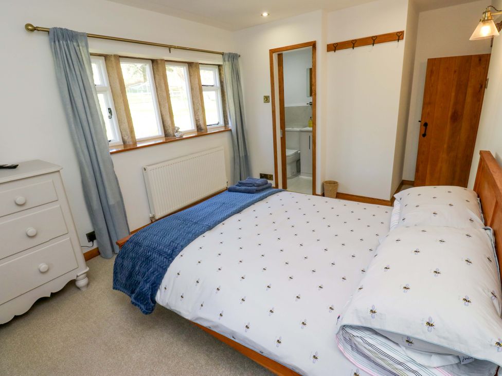 A bedroom with a bed and windows at Barley Cote Farm in Riddlesden