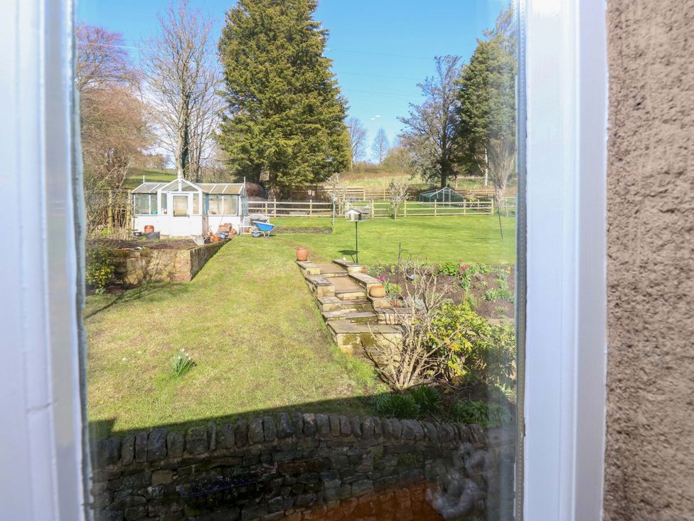A garden view with a greenhouse and lawn at Barley Cote Farm in Riddlesden