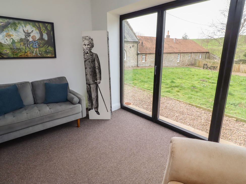 A living room with a sofa and cutout near a window at Honeysuckle Cottage in Crookham near Cornhill-On-Tweed