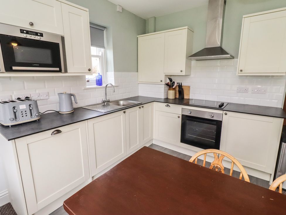 A kitchen with cabinets, sink, and appliances at Honeysuckle Cottage in Crookham near Cornhill-On-Tweed