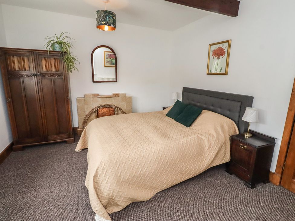 A bedroom with a bed and wardrobe at Honeysuckle Cottage Crookham near Cornhill-On-Tweed