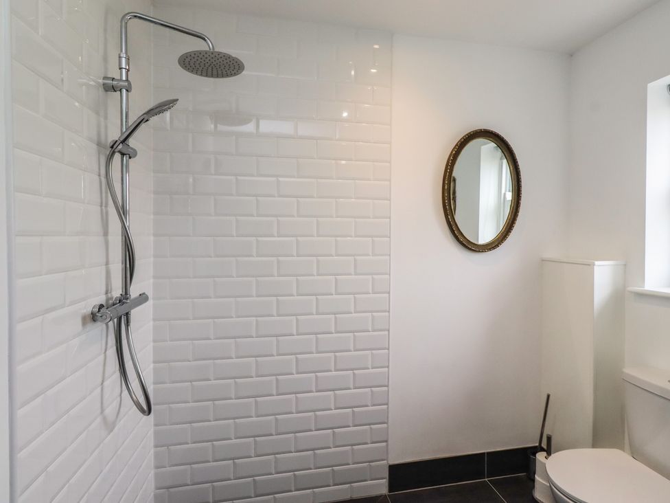 A bathroom with a shower, toilet, and mirror at Honeysuckle Cottage Crookham near Cornhill-On-Tweed