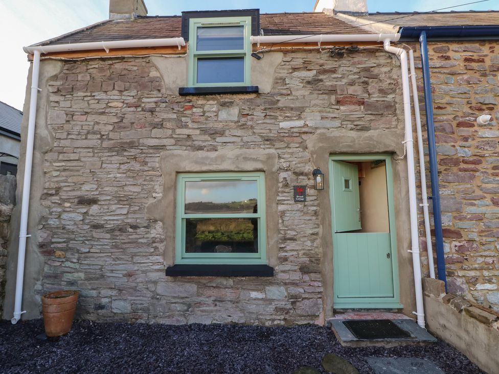 An exterior view of a stone cottage with a green door at 2 Strand Cottages in Carmarthen