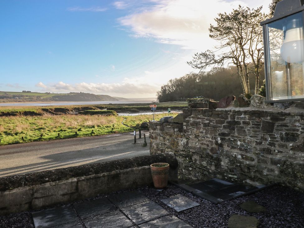 A view of a stone wall and grassy area with water in the distance at 2 Strand Cottages Carmarthen
