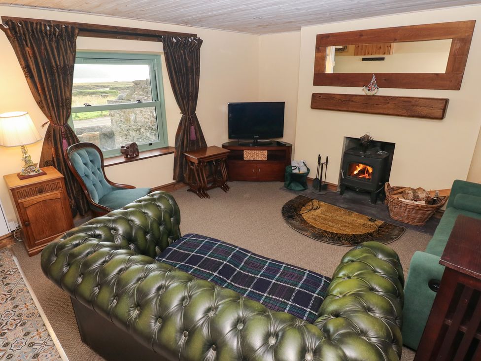 A living room with a sofa and fireplace at 2 Strand Cottages in Carmarthen