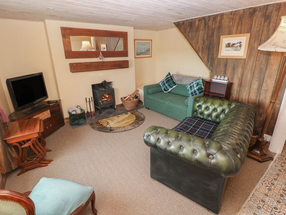 A living room with a fireplace and television at 2 Strand Cottages in Carmarthen