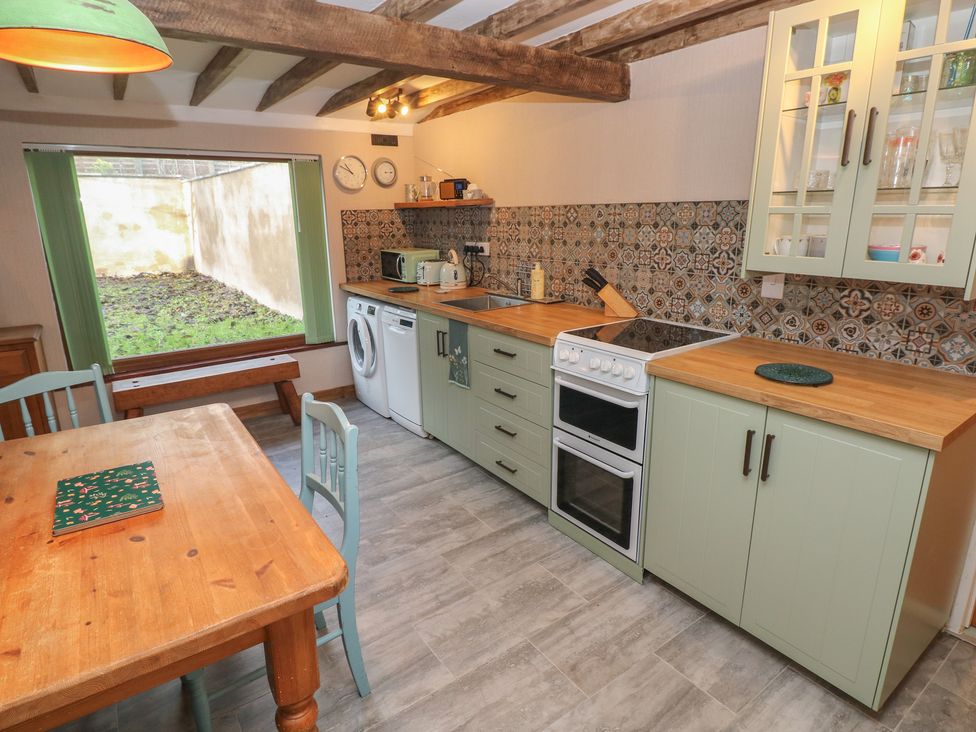 A kitchen with a wooden table and chairs at 2 Strand Cottages in Carmarthen