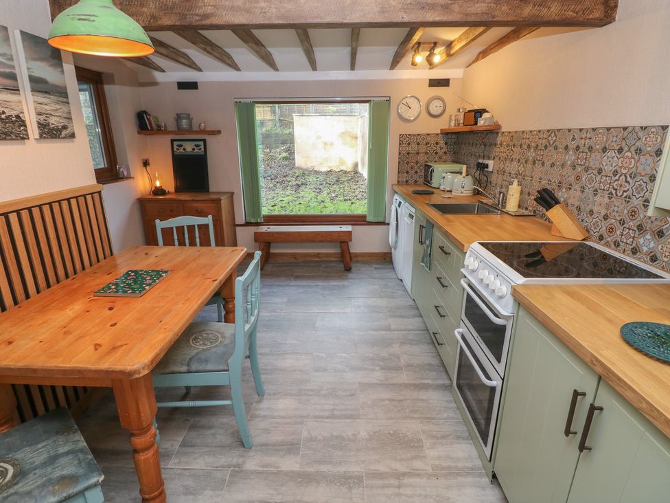 A kitchen with a dining table and various appliances at 2 Strand Cottages in Carmarthen