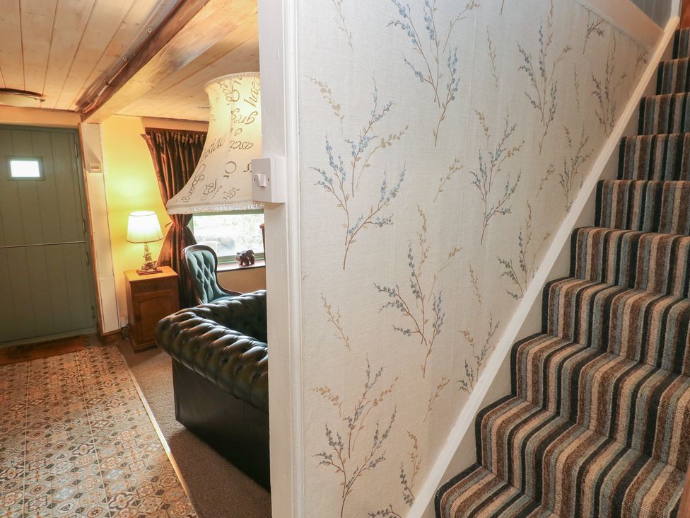 A hallway with a staircase and a sofa at 2 Strand Cottages in Carmarthen