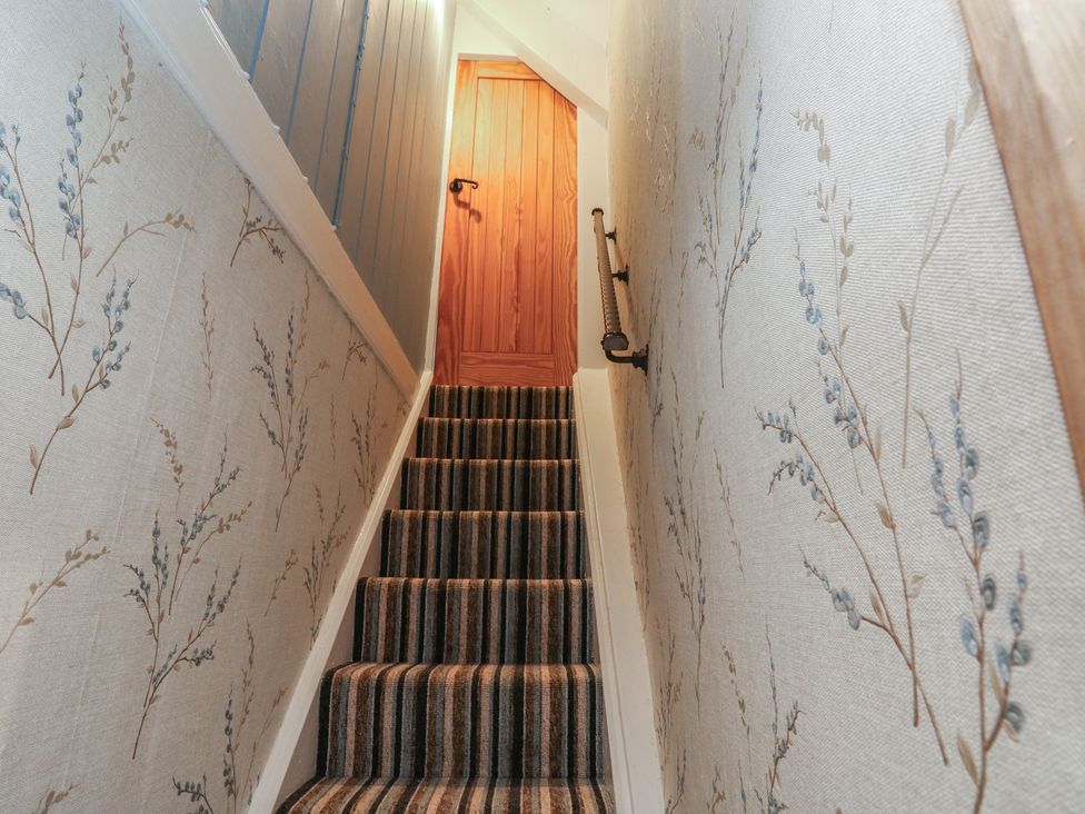 A staircase leading to a door in a hallway at 2 Strand Cottages in Carmarthen