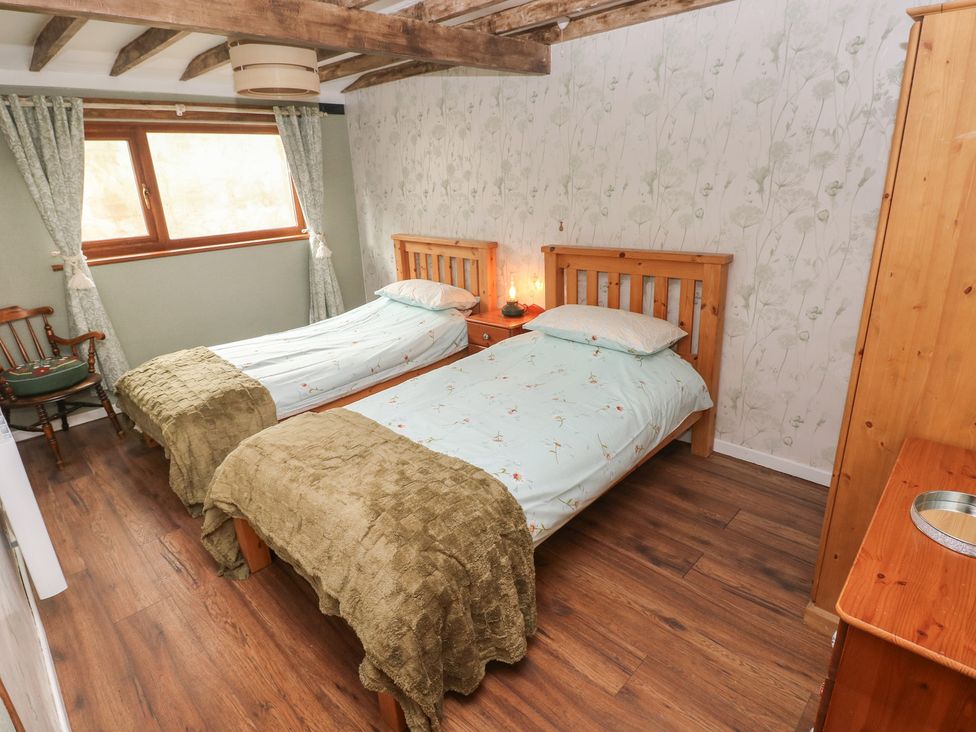 A bedroom with two twin beds and a dresser at 2 Strand Cottages in Carmarthen