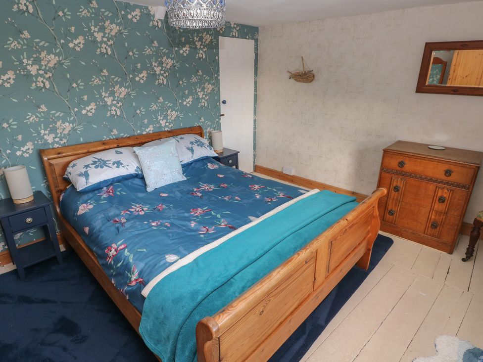 A bedroom with a bed and dressing table at 2 Strand Cottages in Carmarthen