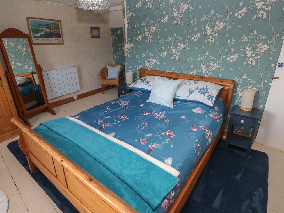 A bedroom with a bed and nightstand at 2 Strand Cottages in Carmarthen