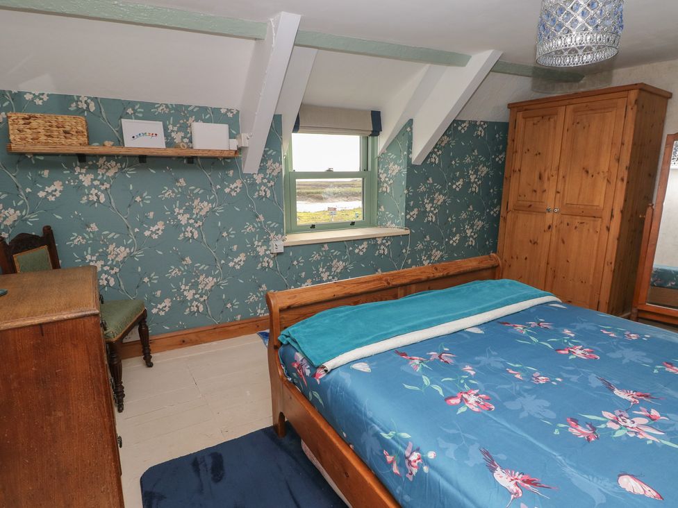 A bedroom with a bed and a wardrobe at 2 Strand Cottages, Carmarthen