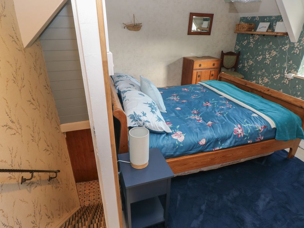 A bedroom with a bed and nightstand at 2 Strand Cottages in Carmarthen