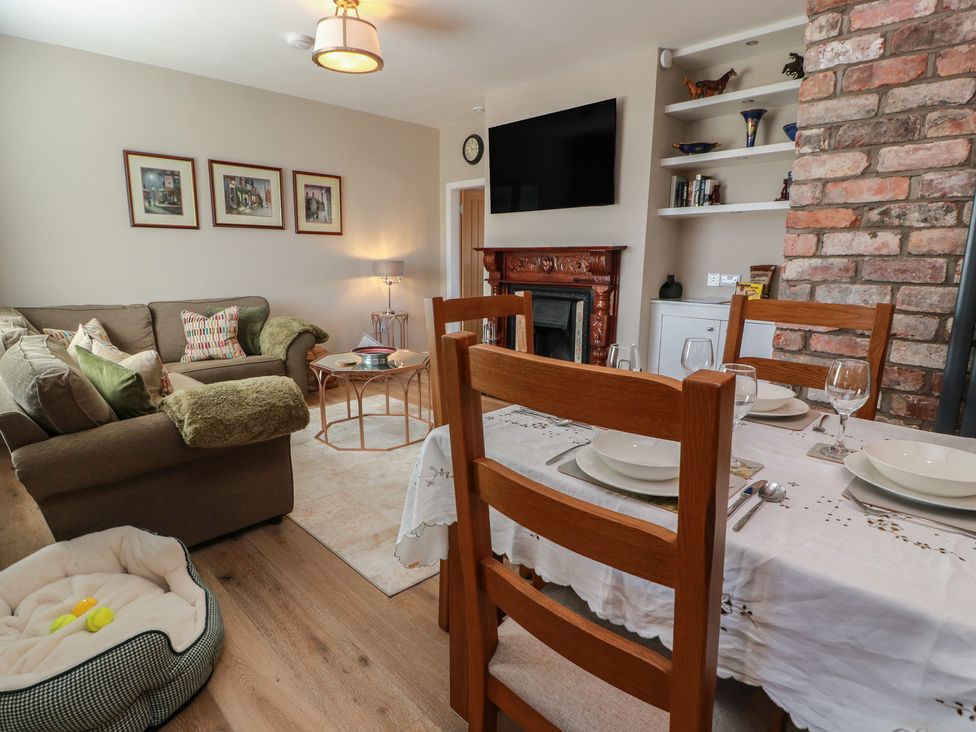 A living room with a dining area and fireplace at Castaway Cottage Maidens