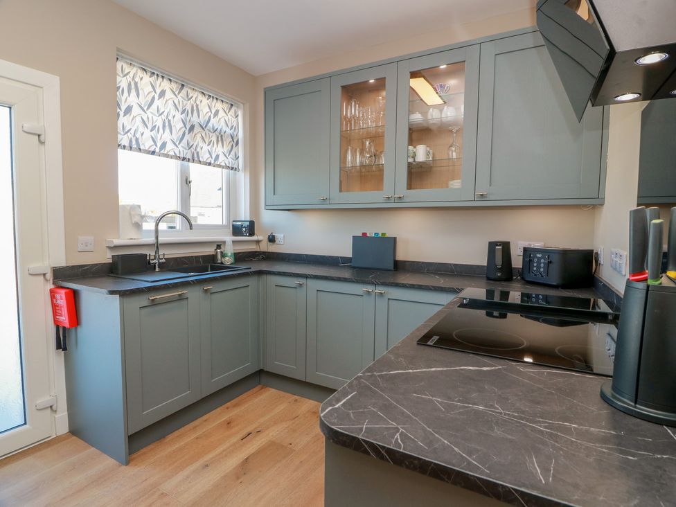 A kitchen with cabinets and appliances at Castaway Cottage Maidens