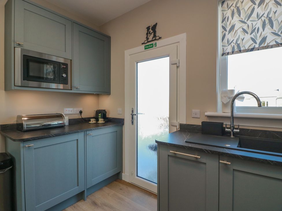 A kitchen with a microwave, sink, and kettle at Castaway Cottage Maidens