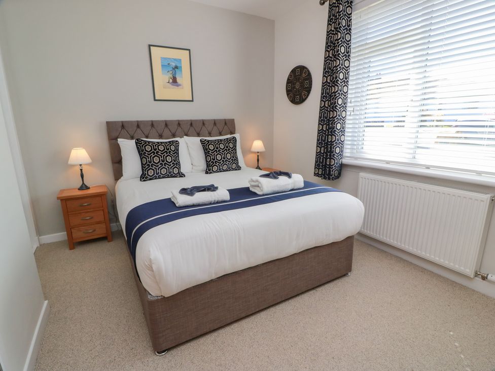 A bedroom with a bed and nightstand at Castaway Cottage Maidens