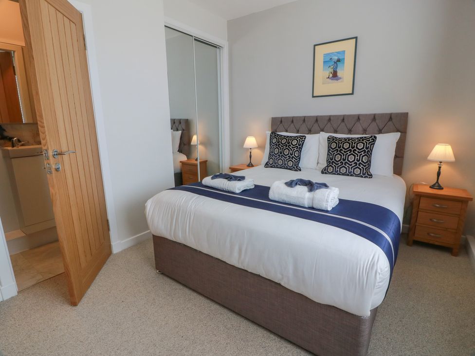 A bedroom with a bed and nightstands at Castaway Cottage Maidens