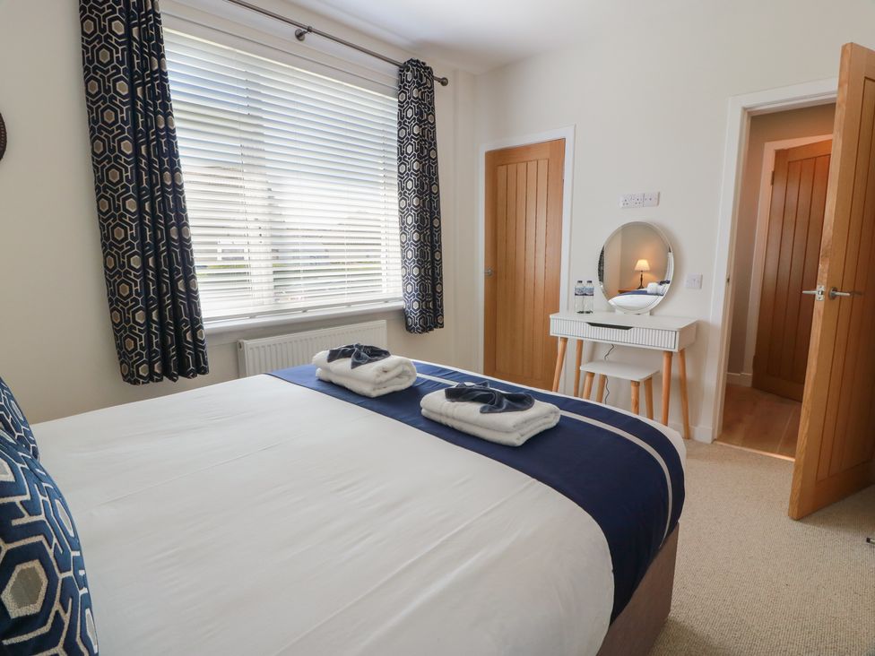 A bedroom with a bed and mirror at Castaway Cottage Maidens