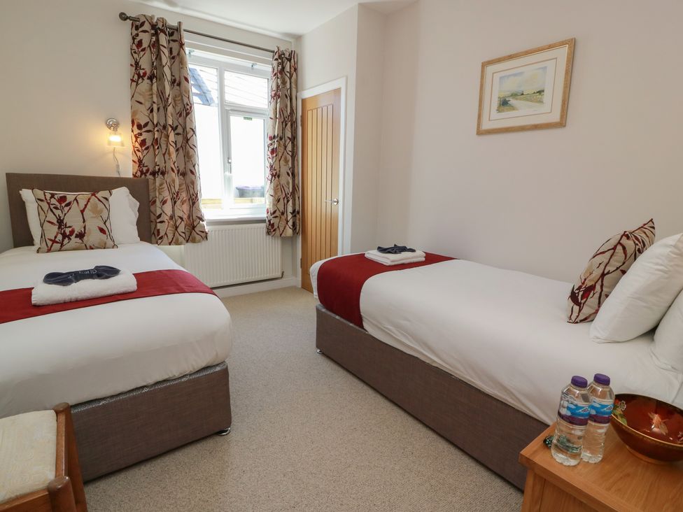 A bedroom with two beds and a window at Castaway Cottage Maidens
