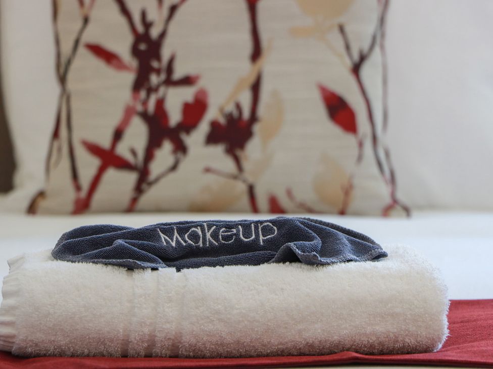 A makeup towel on top of a white towel in a bedroom setting at Castaway Cottage Maidens