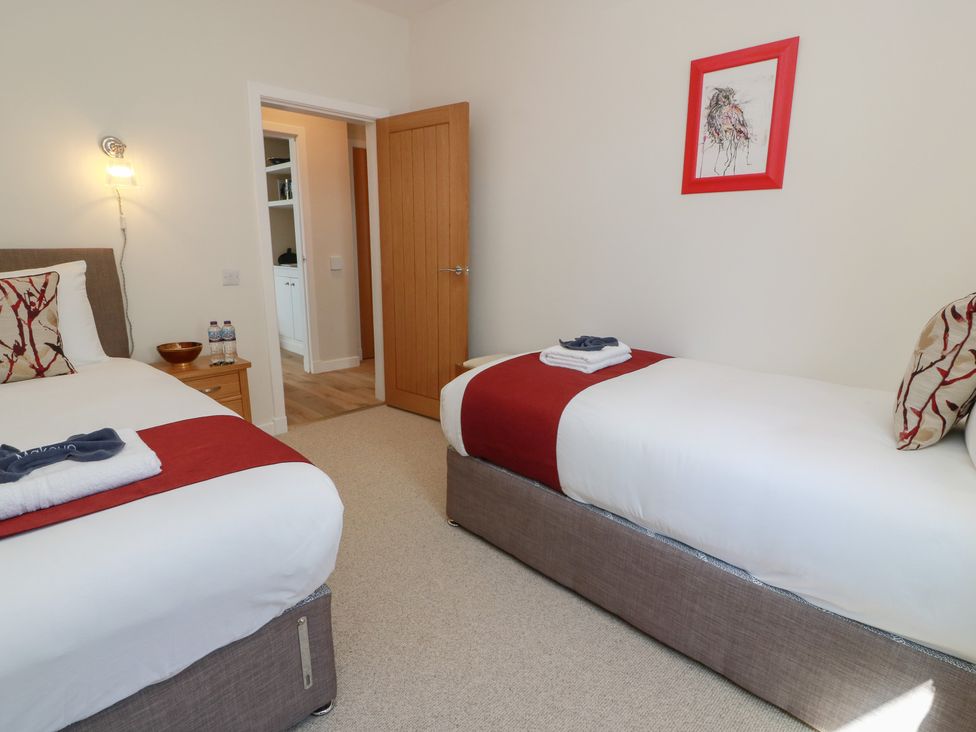 A bedroom with two beds and a nightstand at Castaway Cottage Maidens