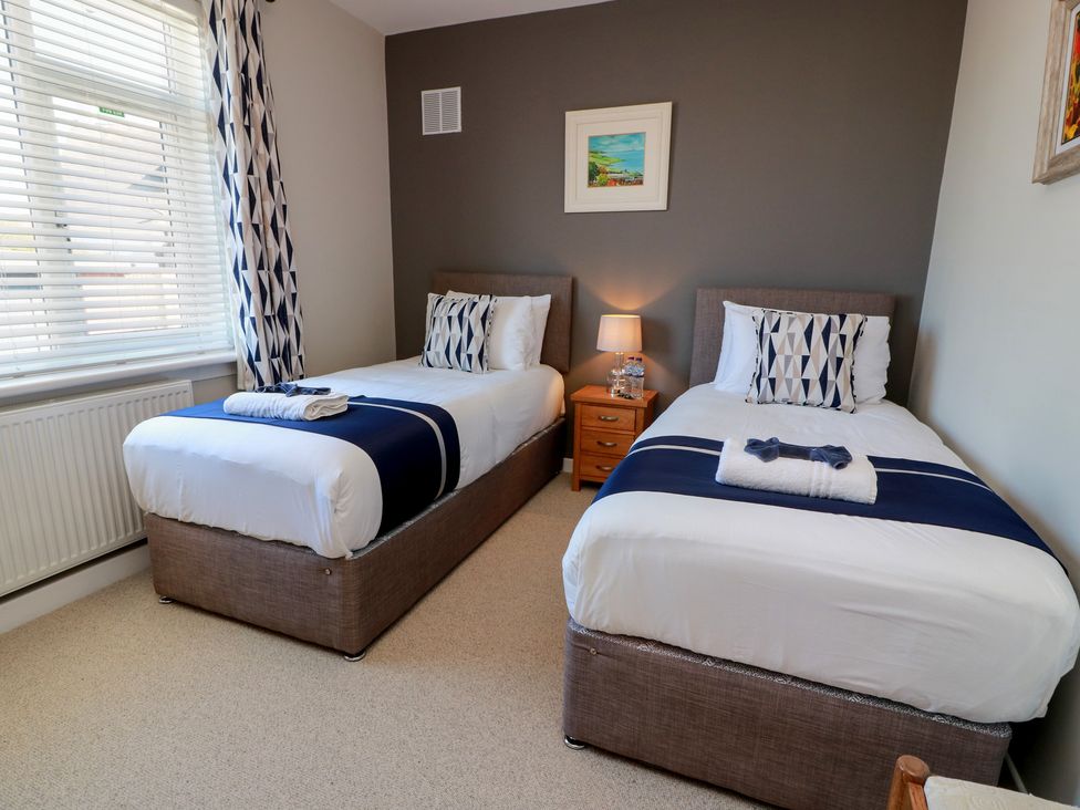 A bedroom with twin beds and a bedside table at Castaway Cottage Maidens