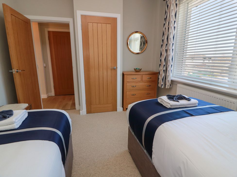 A bedroom with two beds and a drawer unit at Castaway Cottage Maidens