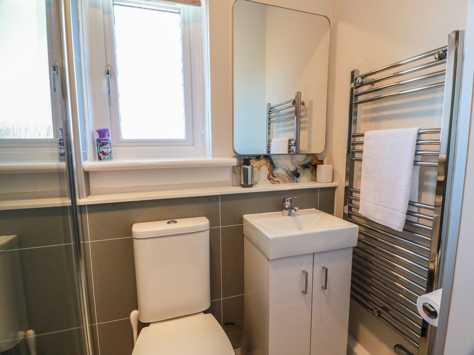 A bathroom featuring a toilet, sink, mirror, and towel rail at Castaway Cottage Maidens