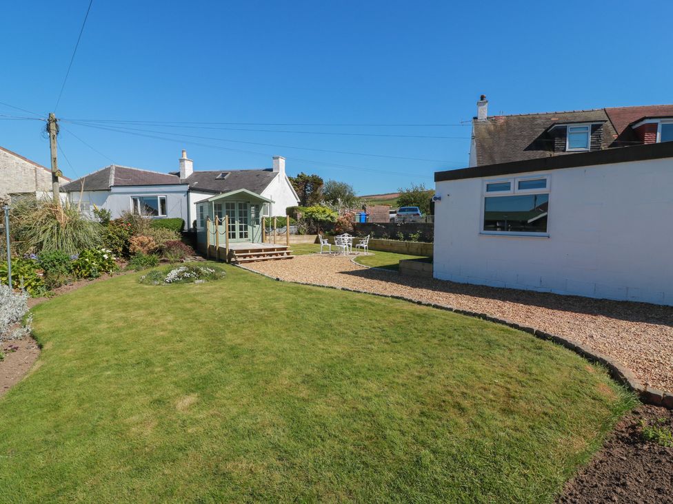 A garden with a house and patio area at Castaway Cottage Maidens