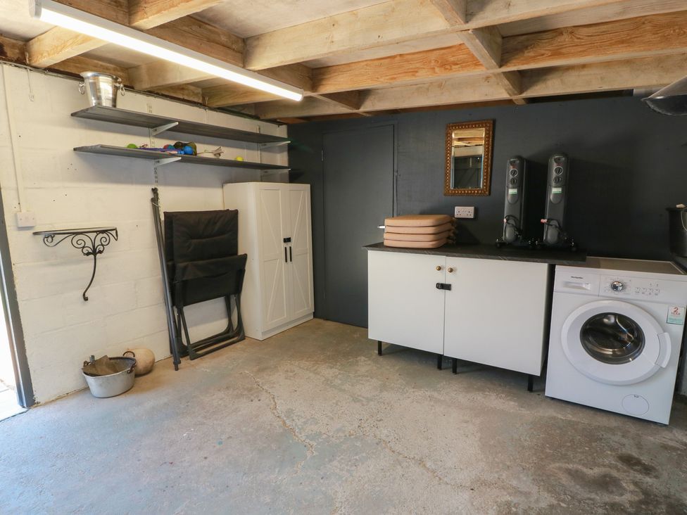 A utility room with a washing machine and storage cabinet at Castaway Cottage Maidens
