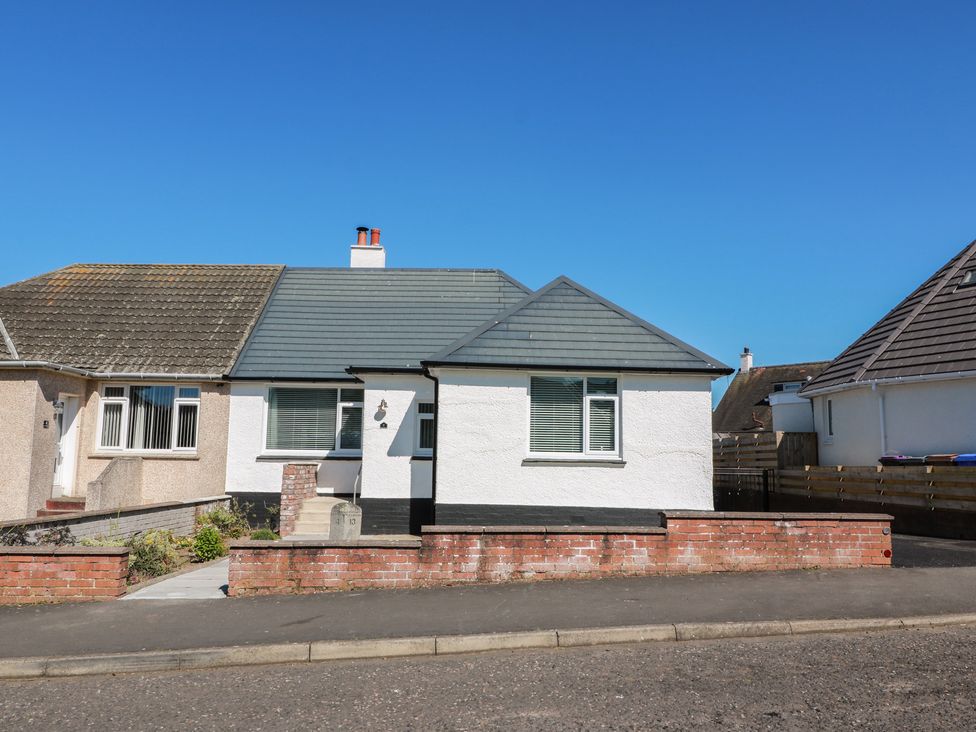 A bungalow with a grey roof and front yard at Castaway Cottage Maidens