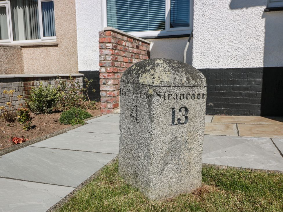 A milestone with the numbers 4 and 13 in front of a house at Castaway Cottage Maidens