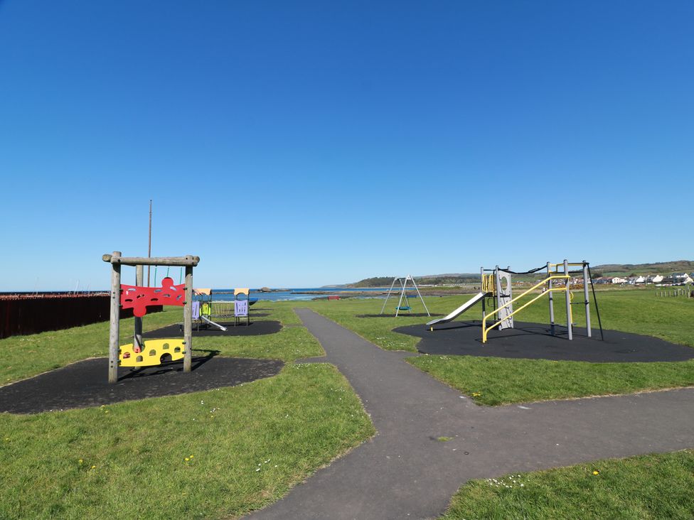 A playground with swings and slides near the coast at Castaway Cottage Maidens in Maidens
