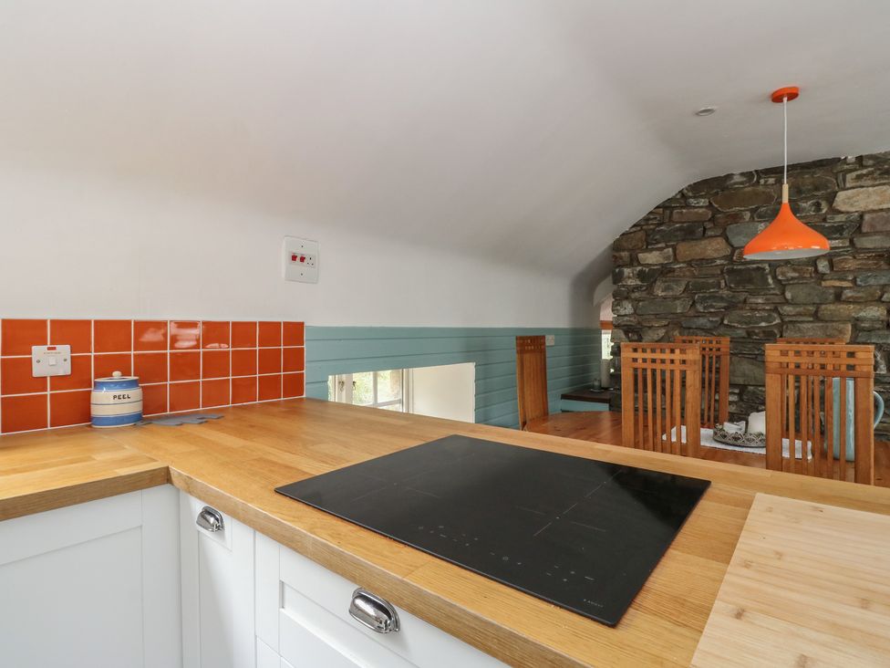 A kitchen with a stove and dining chairs at Culearn Mill in Balquhidder, Perthshire, Scotland