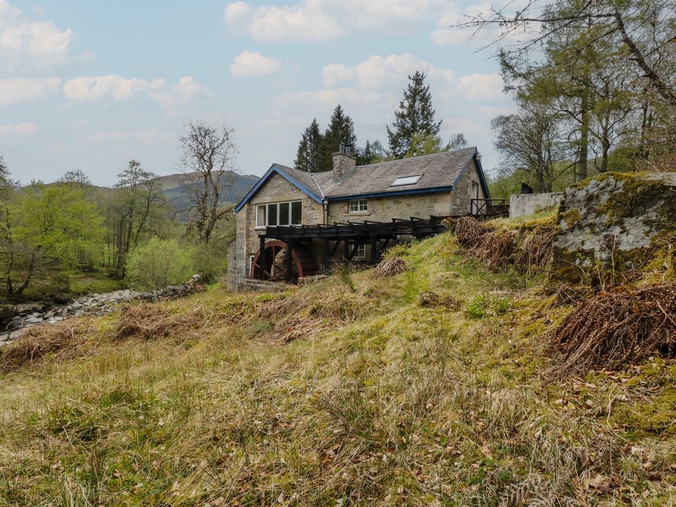 A house with a water wheel and deck in an outdoor area at Culearn Mill, Balquhidder, Perthshire, Scotland