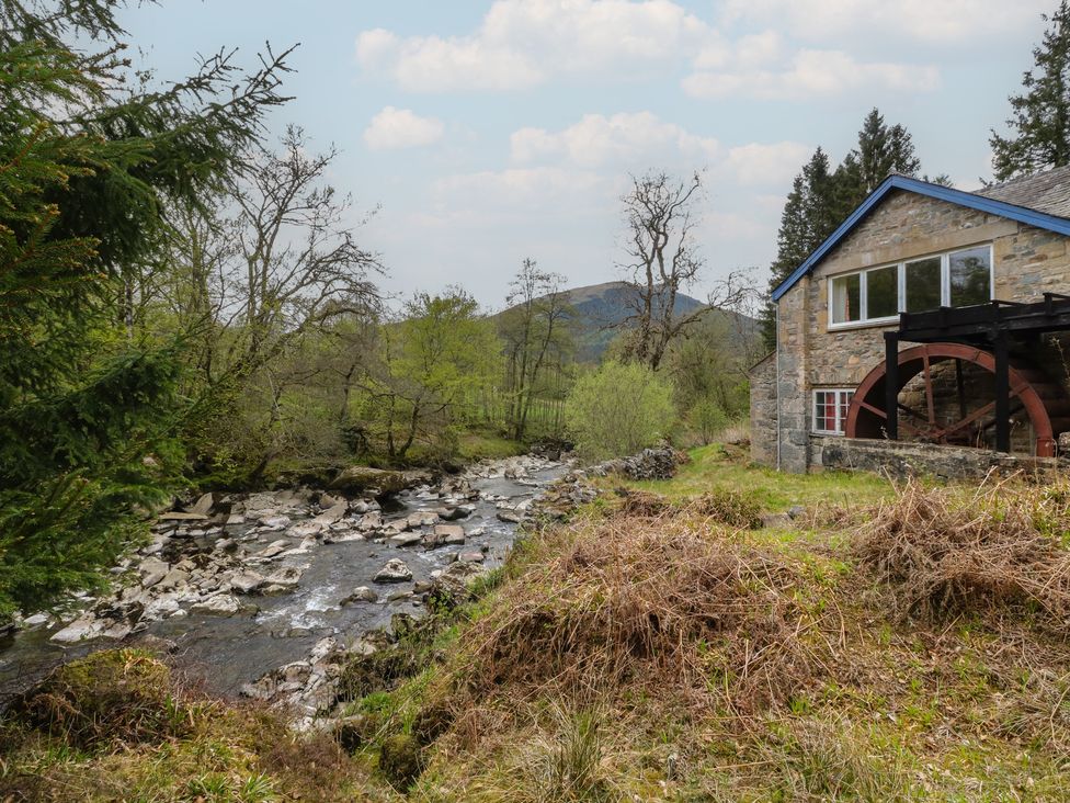 A building with a water wheel next to a river at Culearn Mill in Balquhidder, Perthshire, Scotland